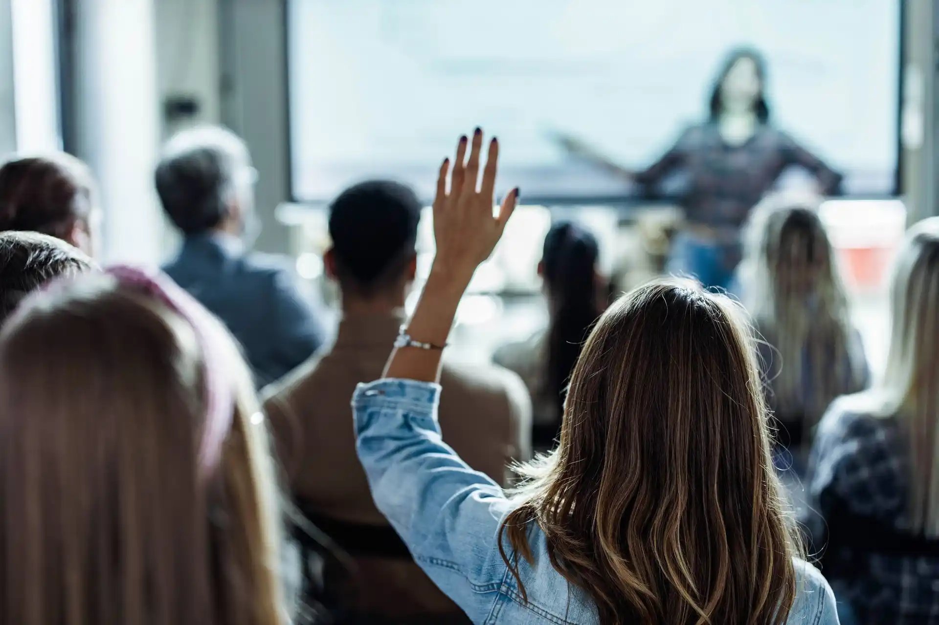 woman raising hand at conference